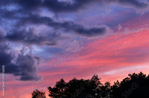 A stunning sunset with a red and blue clouds over the forest.