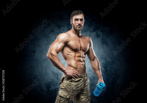 Muscular young man in studio on dark background © bondarchik