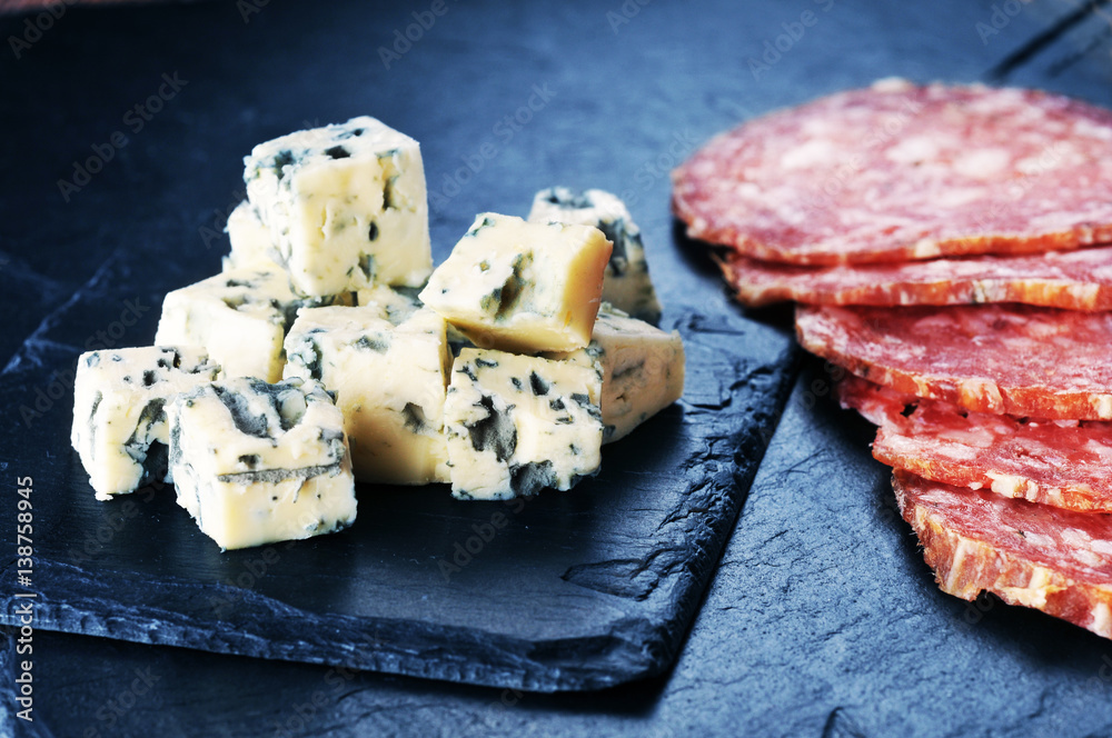 Fresh cheese and sausages on the bdark blue background Fresh cheese and sausages on the bdark blue background