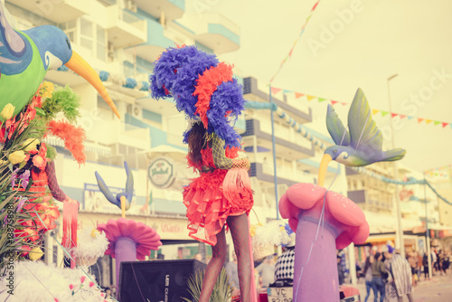 Fotótapéta Blurry defocused silhouette of unrecognizable joyful dancing woman wearing carnival feathers costume on sunny street outdoors background