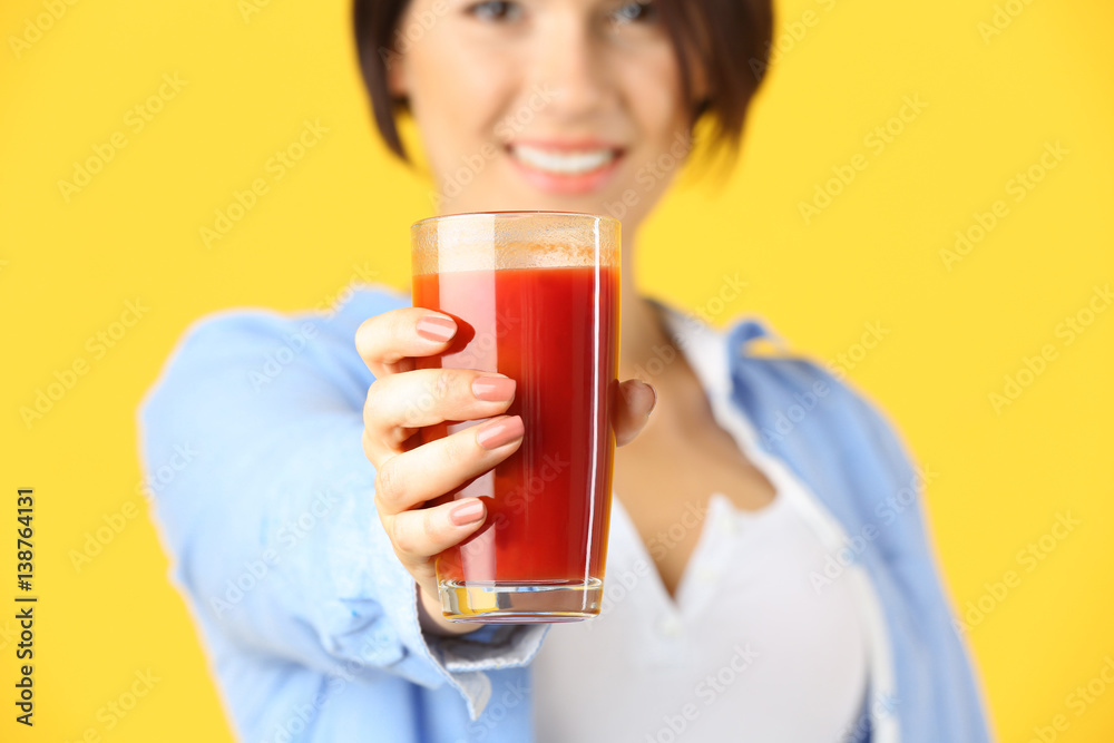 Young beautiful woman with glass of tomato juice, on yellow background Young beautiful woman with glass of tomato juice, on yellow background