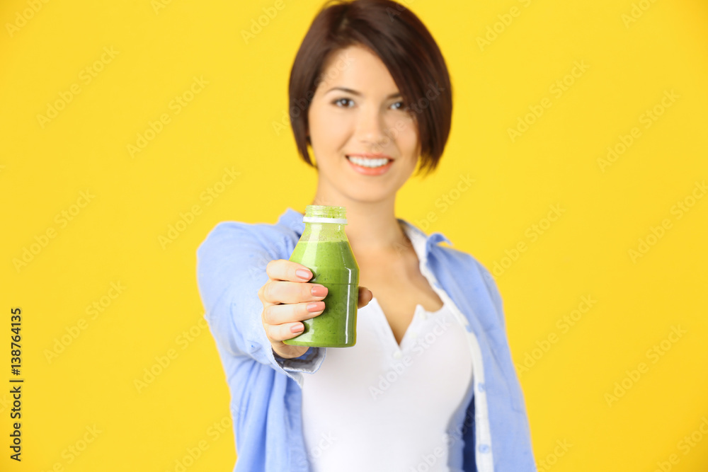 Young beautiful woman with green smoothie, on yellow background Young beautiful woman with green smoothie, on yellow background