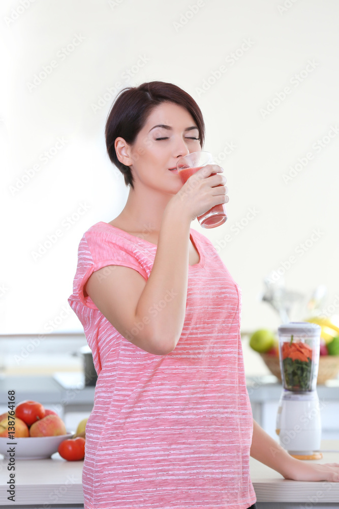 Young beautiful woman with peach juice in the kitchen Young beautiful woman with peach juice in the kitchen