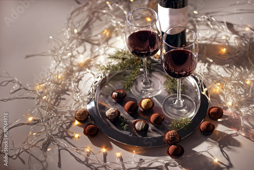 Glasses of red wine and chocolate truffles on decorated table