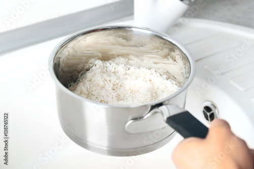 Woman rinsing rice in saucepan