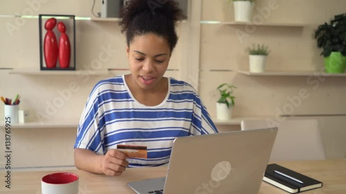 Mixed race woman shopping online. satisfied customer buy remote using internet and laptop holding credit card. photo