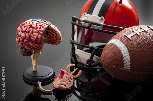 Brain damage and sports injury concept with damaged brain model, american football helmet and a ball, illustrating CTE (Chronic traumatic encephalopathy) a syndrome caused by repeated concussion photo