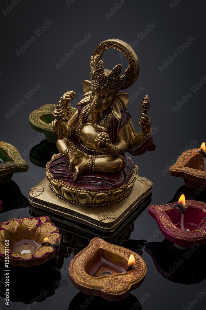 Hindu religion and Indian celebration of Diwali festival concept with diya lamps and candles around the Lord Ganesh. Ganesha is the patron of arts and sciences and the deva of intellect and wisdom