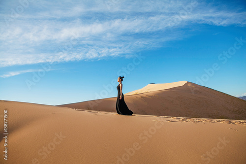 Fashion woman model posing in long black dress in desert