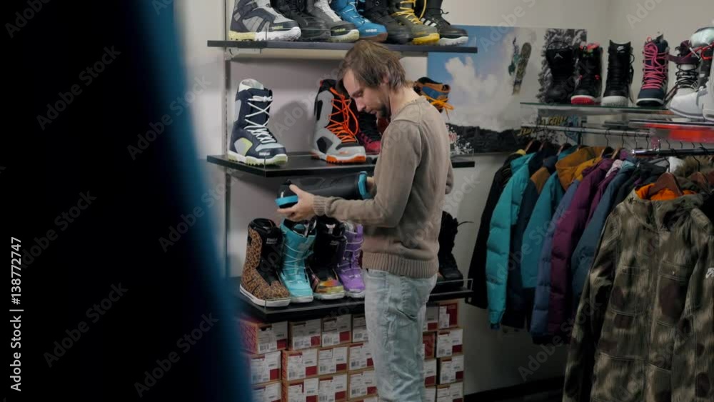 Man chooses a snowboard boot in sport store, extreme shopping Man chooses a snowboard boot in sport store, extreme shopping