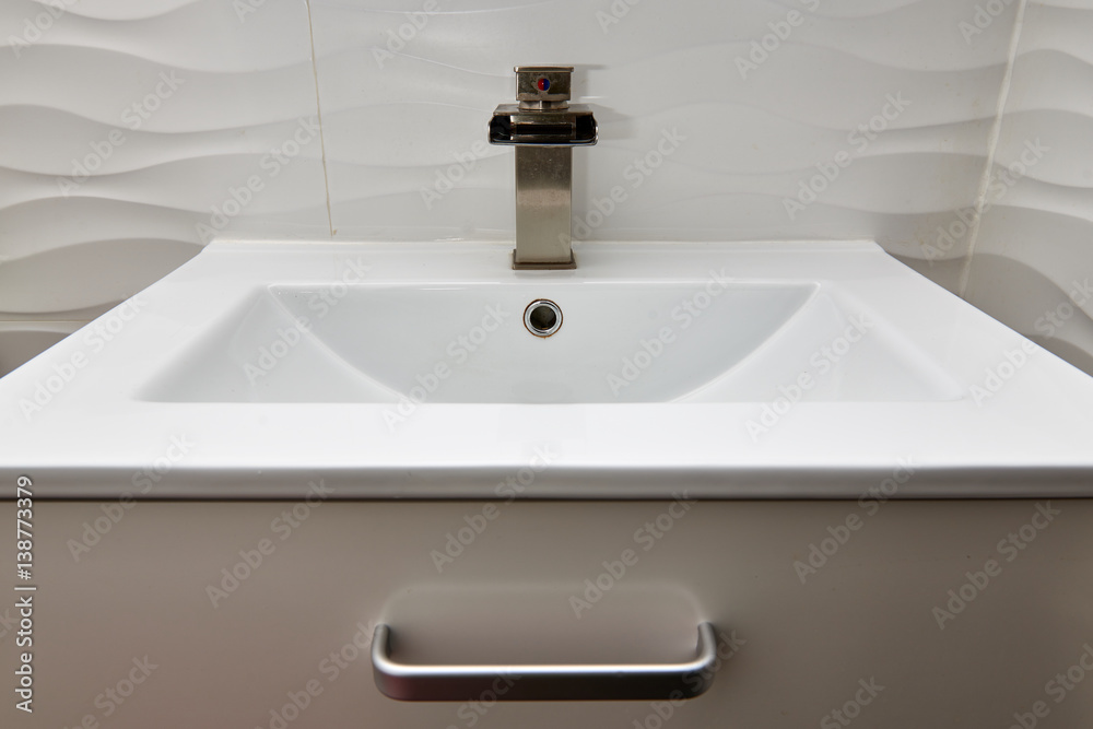 Fototapeta premium White modern design bathroom vanity with white marble sink and brushed nickel waterfall faucet
