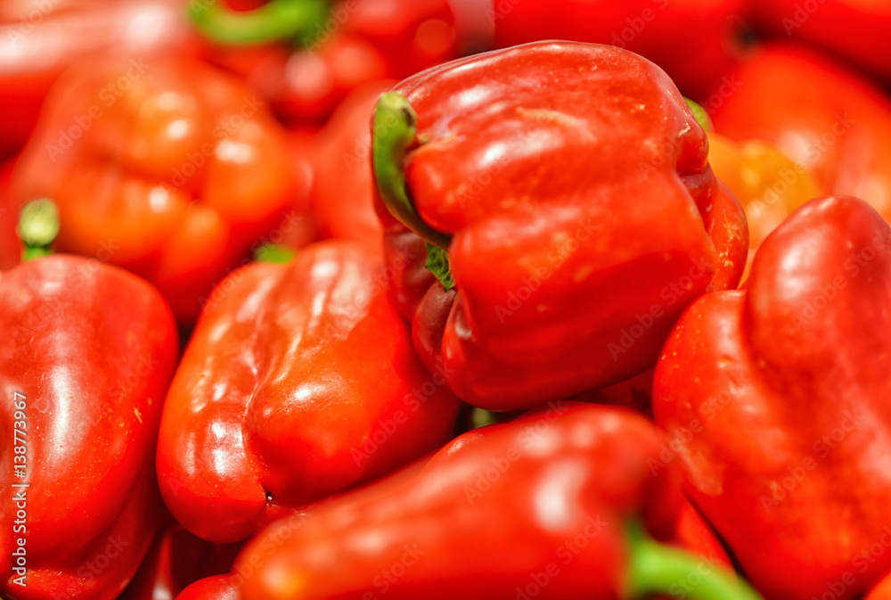 Red bell peppers on a counter in the supermarket. A large number of red peppers in a pile