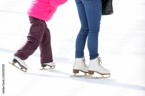 child and adult skates at the ice rink.