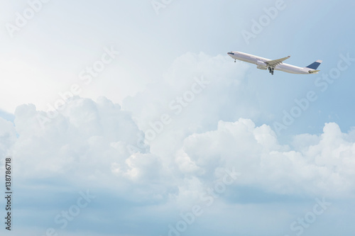 Fototapeta Komercyjny samolot odlatujący z lotniska lecący nad jasnym błękitnym niebem i białymi chmurami na niebie