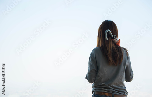 young woman standing on a cliff rock with sunlight