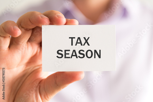 Businessman holding a card with TAX SEASON message