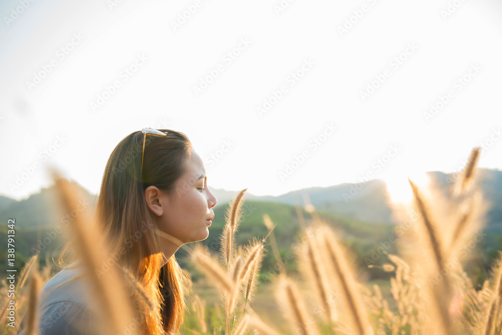Woman standing in the midst of a beautiful natural grass happily.