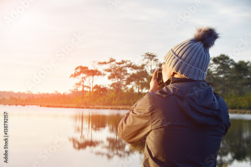 man take photo near lake at morning. subject is blurred