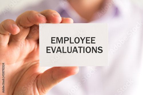 Businessman holding a card with EMPLOYEE EVALUATIONS message