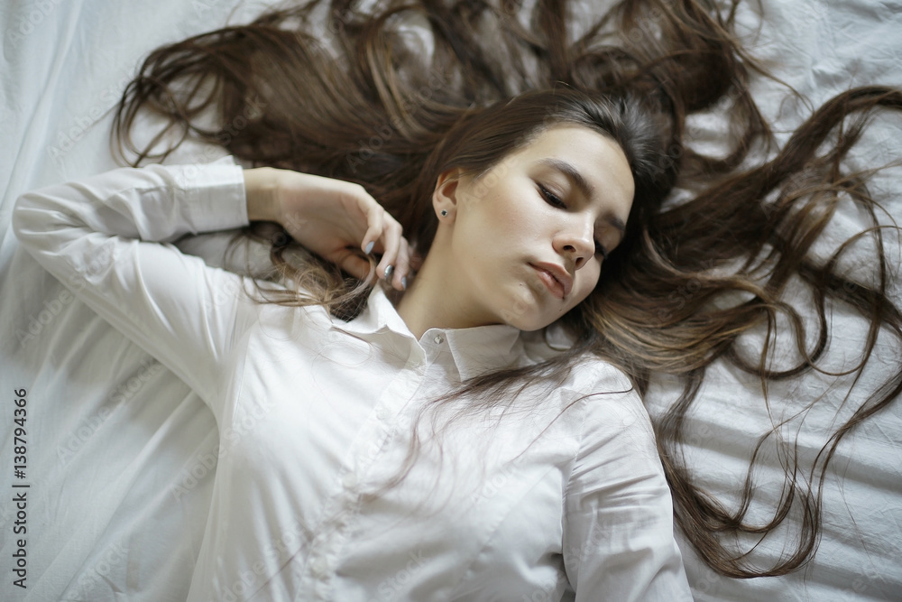 Brunette beautiful young adult with long hair lying on the bed Brunette beautiful young adult with long hair lying on the bed