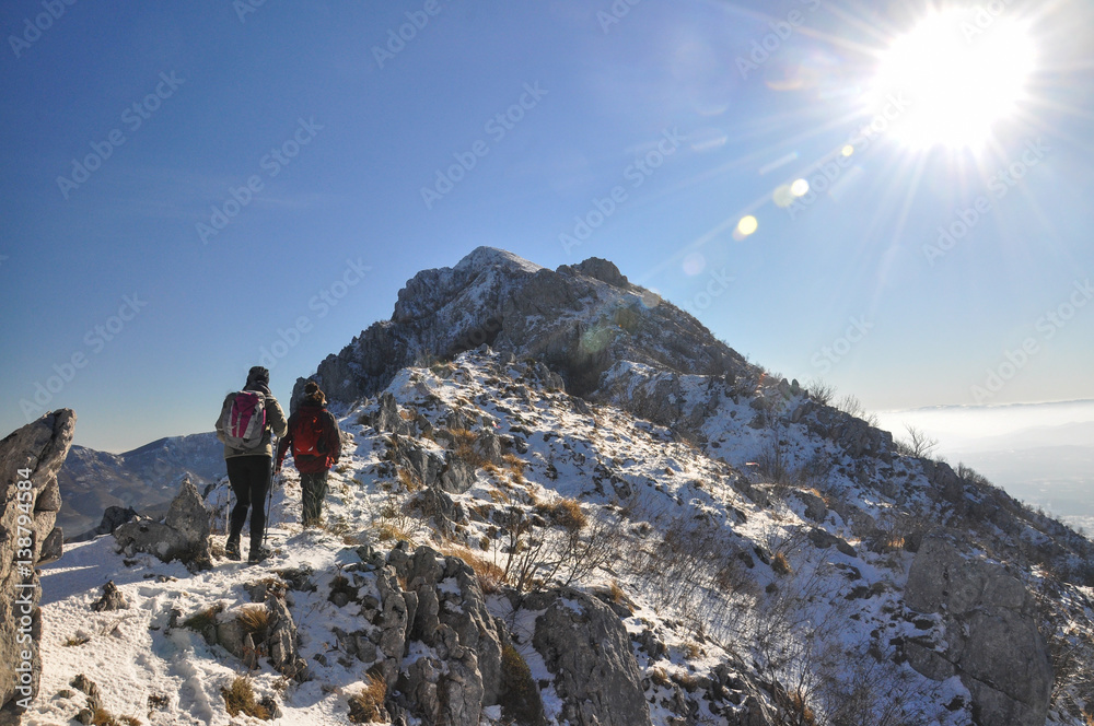 Couple of mountaineers hiking on snowy mountain into the sun