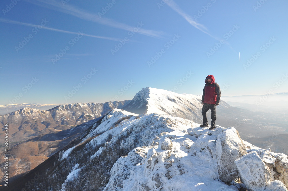 Lonely mountaineer get rest on snowy mountain high above the clouds into the sun