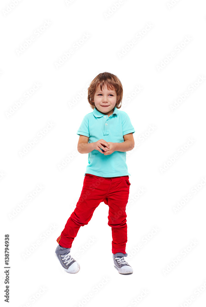 Full body portrait of shy little boy dressed in bright colorful clothes standing giggling and posing awkwardly against white background Full body portrait of shy little boy dressed in bright colorful clothes standing giggling and posing awkwardly against white background