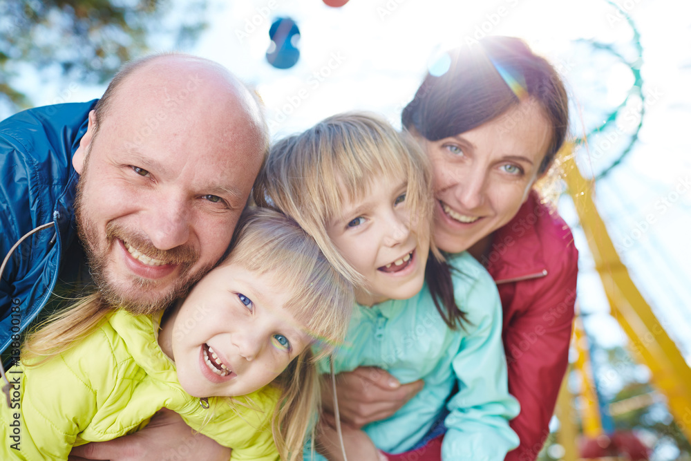 Φωτογραφία Waist-up portrait of happy family of four taking pleasure in spending sunny day