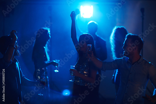 Students relaxing in fashionable night club, dancing with champagne glasses and chatting in the dark © pressmaster