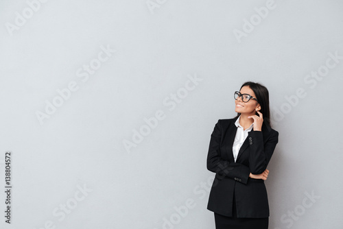 Business woman in eyeglasses thinking and looking away