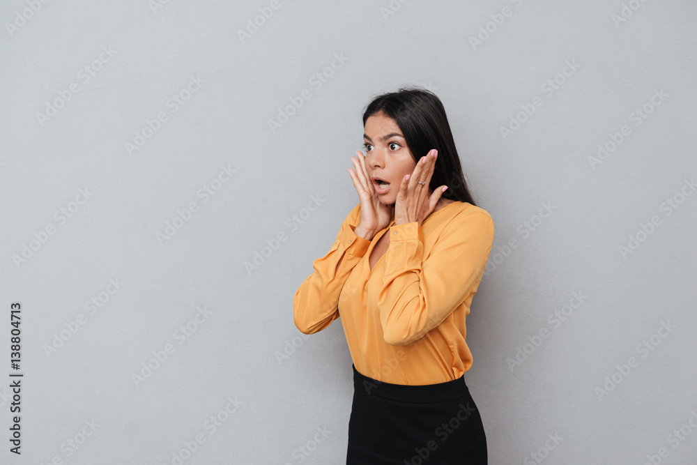 Shocked business woman with her arms on face looking away Shocked business woman with her arms on face looking away