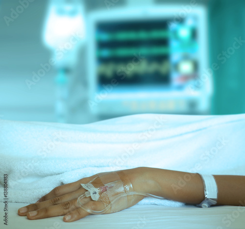 Patient s hand with iv solution set and monitors blur background