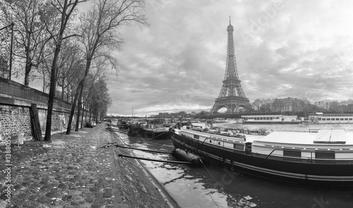 Beautiful panoramic view of the Eiffel Tower and Jena bridge from the river Seine embankment. Dramatic cloudscape. Traditional citycape in backlit morning sunbeam. BW photography. Paris  France.