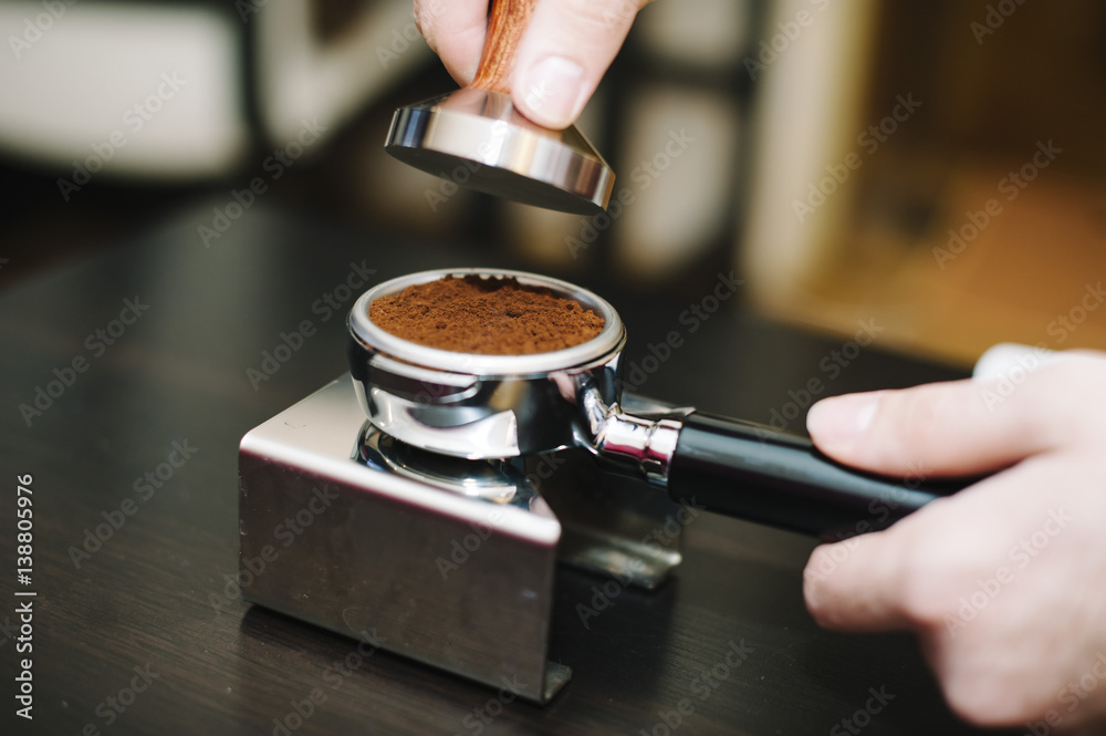 man using a tamper to press freshly ground coffee into a tablet man using a tamper to press freshly ground coffee into a tablet