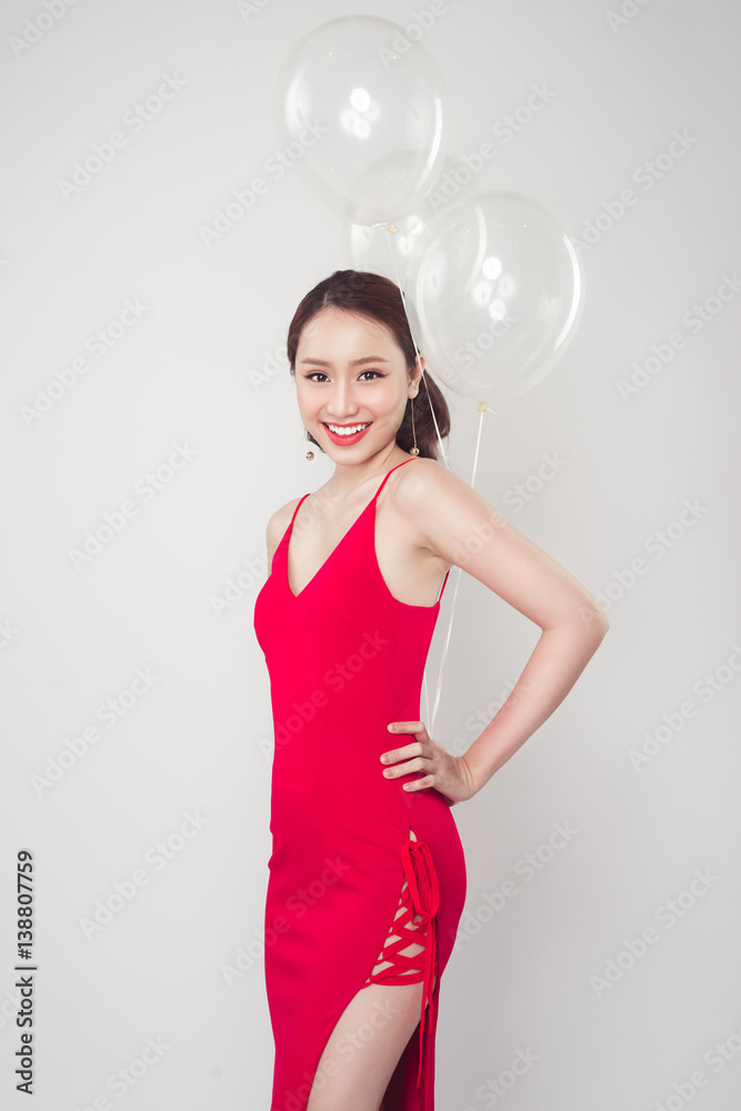 Pretty young asian woman wearing red dress with balloons in hand. Pretty young asian woman wearing red dress with balloons in hand.