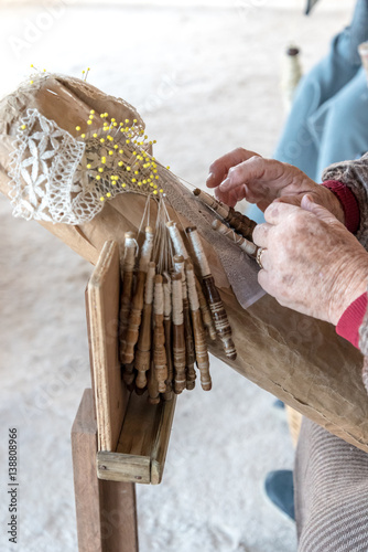 An elderly woman working on hand-made lace or bizzilla