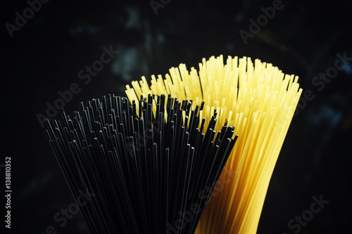 Uncooked spaghetti with tomatoes, black background, selective focus