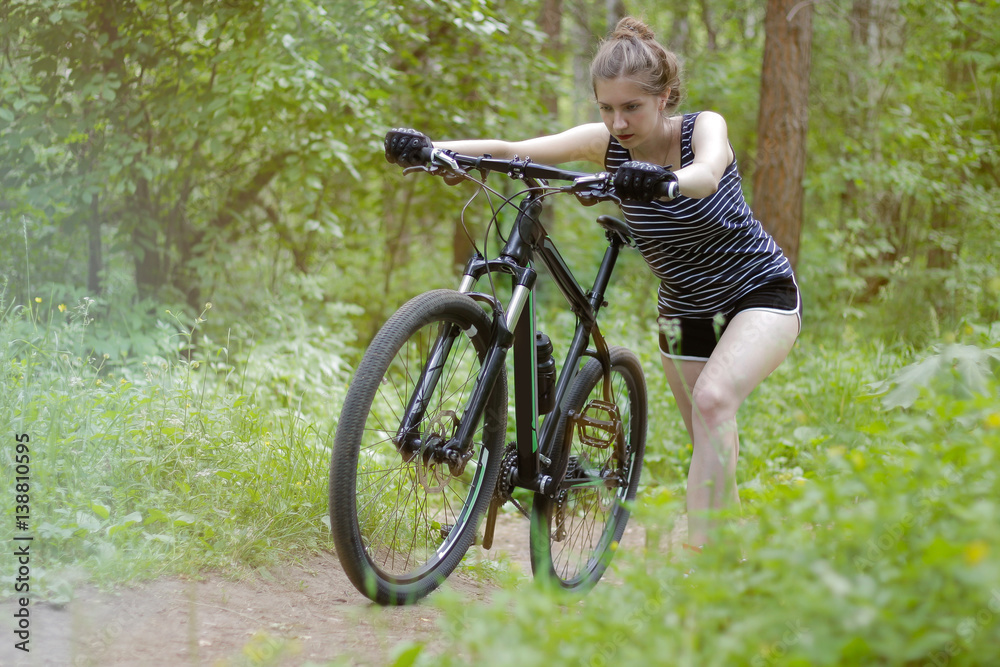 Beautiful girl is riding a mountain bike through the woods on a Sunny day.
