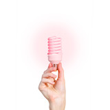 Closeup of man's hand holding energy saving lamp. Glows brightly with red light. Recycling, electricity, environment and ecology concept. The lamp is red. Isolated on white background