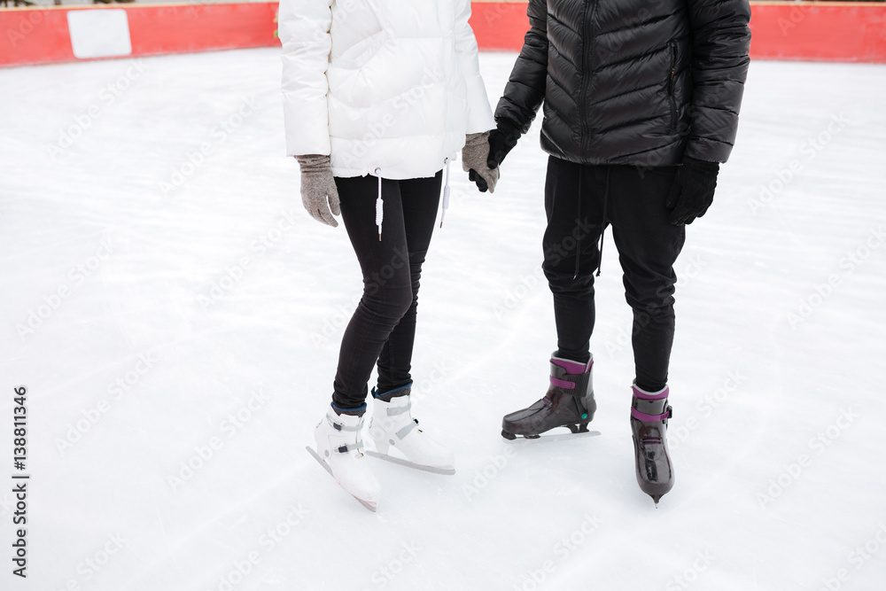 Cropped image of young loving couple skating at ice rink Cropped image of young loving couple skating at ice rink