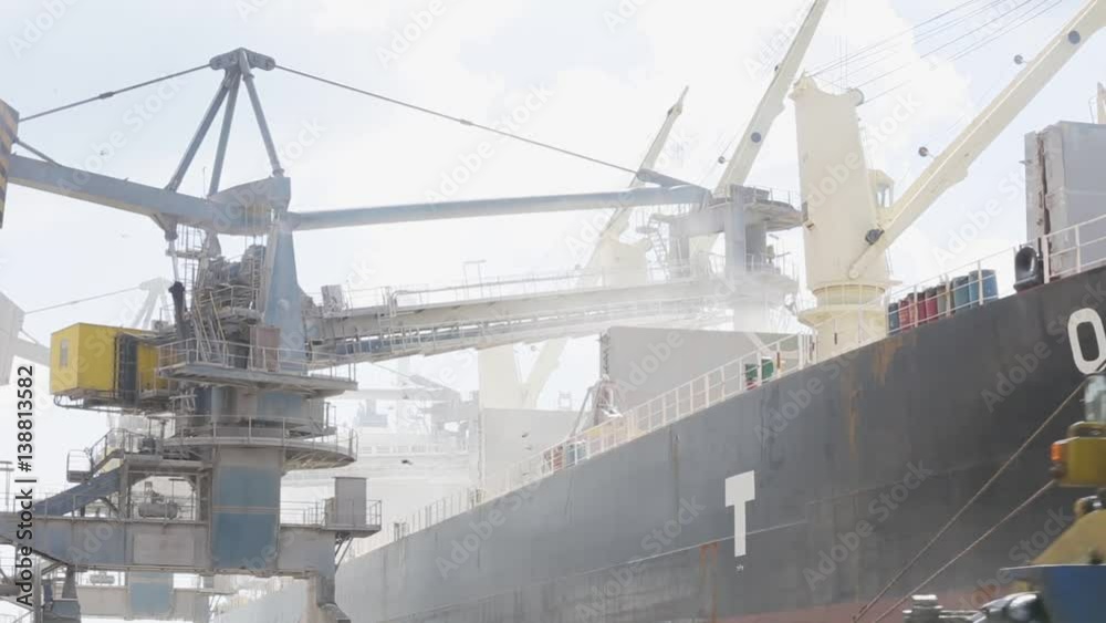 Crane in port loads grain on big ship Crane in port loads grain on big ship