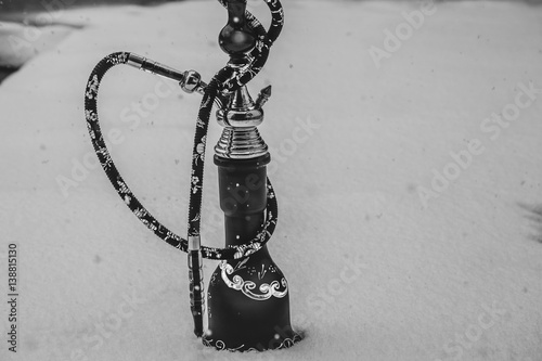 Big hookah for tobacco made of metal, glass and ceramics. Snowing. Snow background. White photo