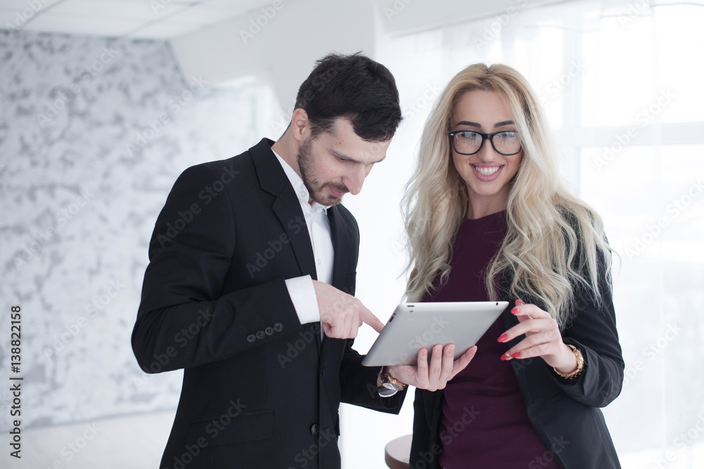 Two confident businesspeople using a digital tablet together while working in a modern office Two confident businesspeople using a digital tablet together while working in a modern office