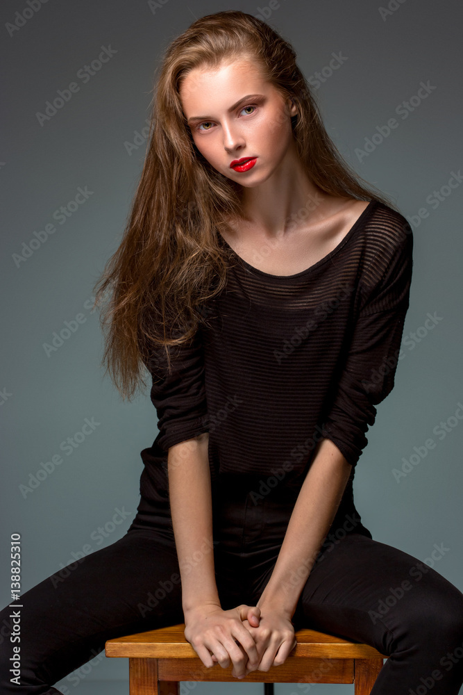 Portrait beauty woman sitting on a chair isolated black background. Portrait beauty woman sitting on a chair isolated black background.