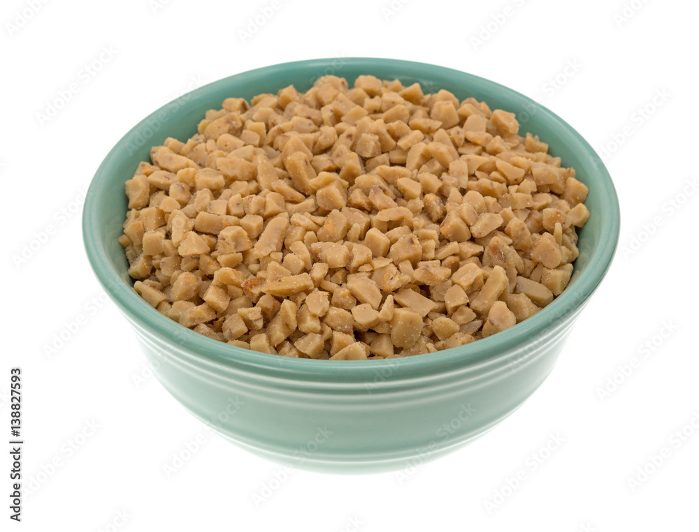 Toffee bits in a green bowl isolated on a white background. Toffee bits in a green bowl isolated on a white background.