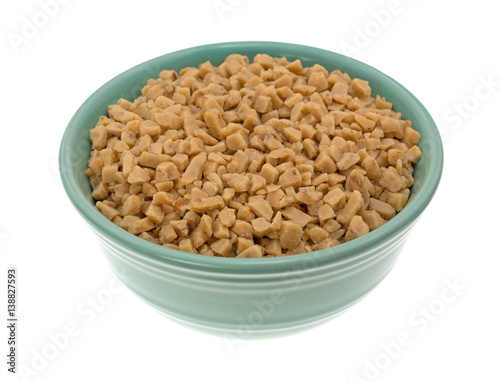 Toffee bits in a green bowl isolated on a white background.