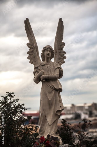 Photography Sculpture of a sad angel on a cemetery against the background of leaves