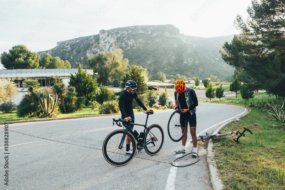 Fototapeta premium Two cyclists fixing a flat tire