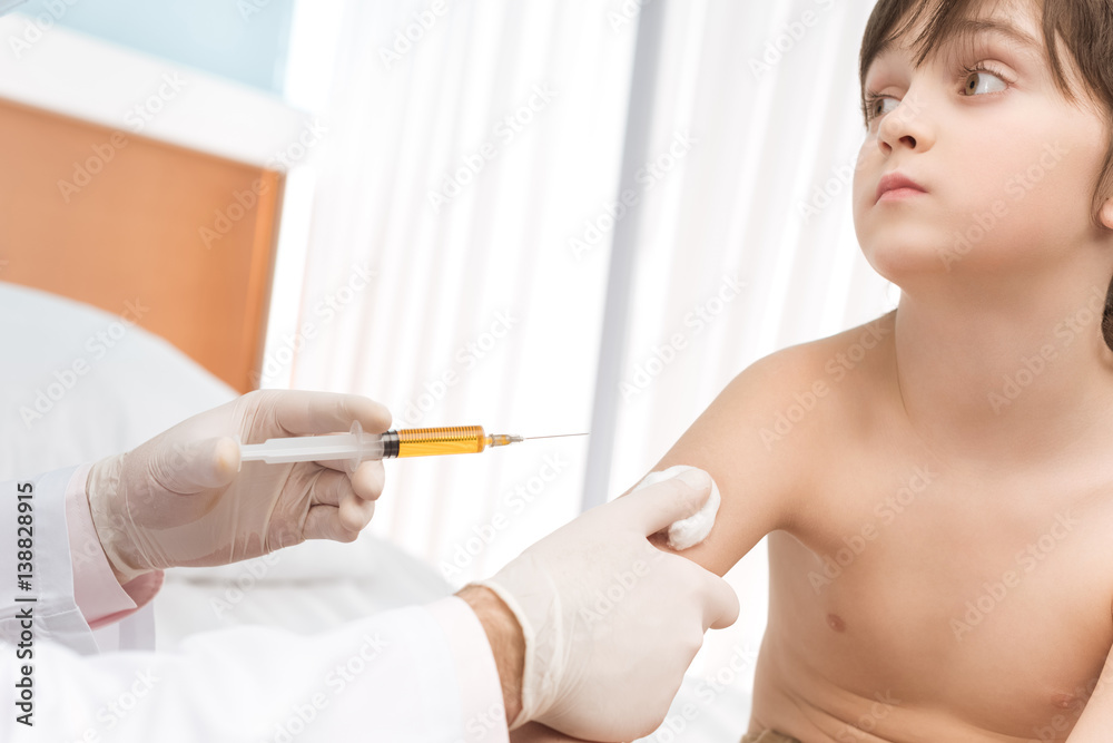 Cropped shot of doctor making injection to little boy in hospital Cropped shot of doctor making injection to little boy in hospital