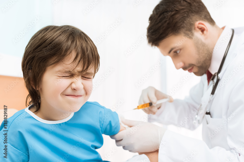 side view of doctor making injection to boy patient in bed side view of doctor making injection to boy patient in bed